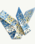 Ottimare twilly dames sjaal met jasmijn bloemen in hemelsblauw en geel met logo in blauw. Het sjaaltje is handgemaakt van dubbele duurzame eco twill kunst zijde in Nederland.