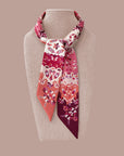 Decorative Ottimare twilly woman's scarf with floral pattern and jasmines on a mannequin in bordeaux, orange and pink colors. Handmade from twill art silk in the Netherlands.