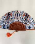 Elegante waaier van Ottimare met print op duurzame kunst zijde met Thangka dansers in donker blauw en sienna oranje. Het frame is van Kotibé hout en handgemaakt in Spanje.