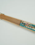 Silk fan displaying two sisters in bright pastels and aqua colours. Handpainted by Ottimare. Artisan production on birch wood, with gold coloured ring attached.