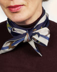 Long tangram scarf Ottimare one dusk blue side and ivory on the back side with multicolored tangram figures. The model wears this extra long cravatte on a burgundy crewneck.