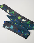 Grey and petrol green tangram scarf with two different colorful sides. Extra long ribbon scarf, wrapped twice around the neck with a bowtie. Ottimare.
