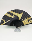 Silk fan handpainted by Ottimare with golden trumpet and black background on a birch wood panisch frame with a satin black coating.