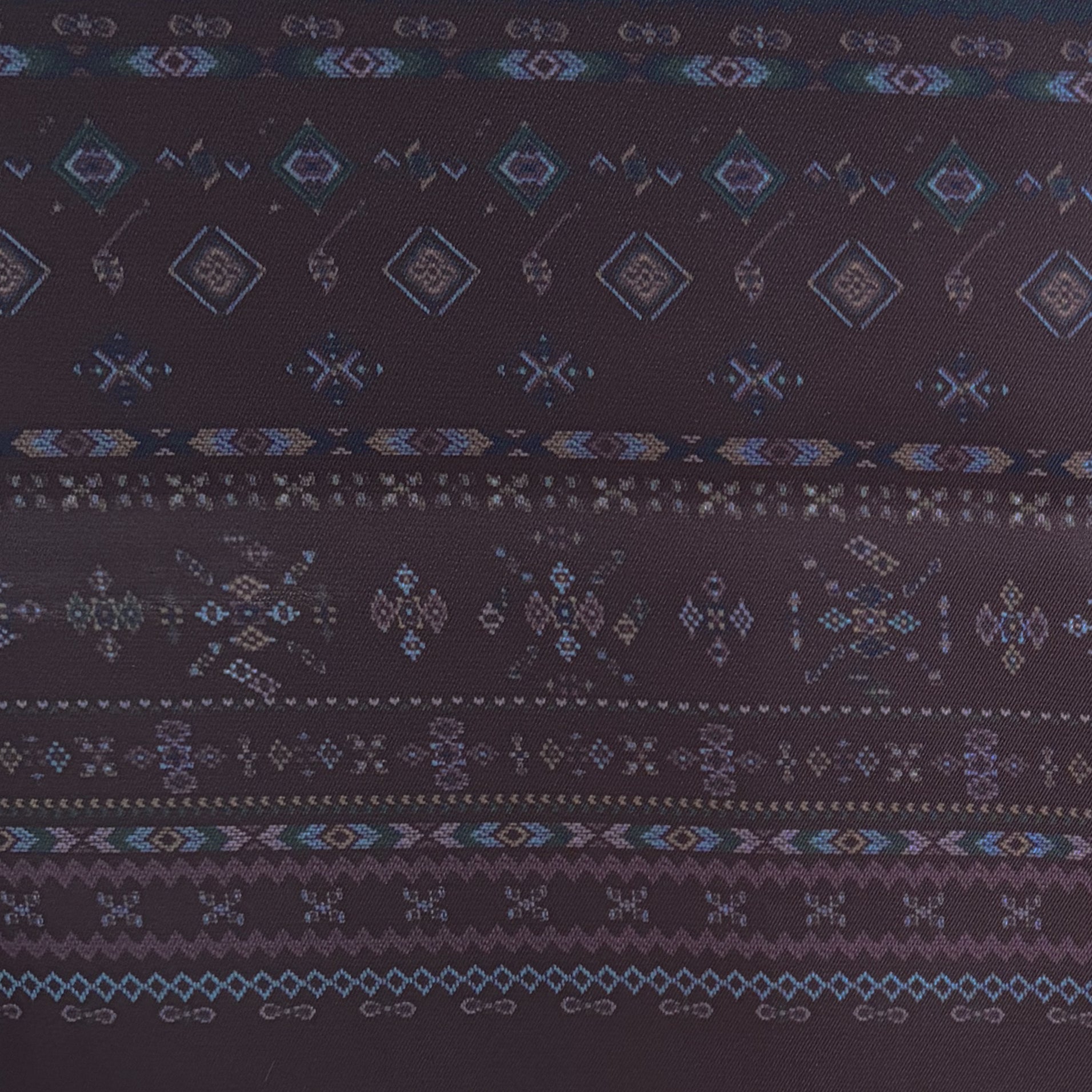 Detail van Ottimare's Kahina sjaal geïnspireerd op Berber motieven. Donker bordeaux achtergrond met accenten in blauw, goudkleur en grijsgroen. De herensjaal die ook door dames gedragen kan worden heeft een franje en is handgemaakt in Nederland.