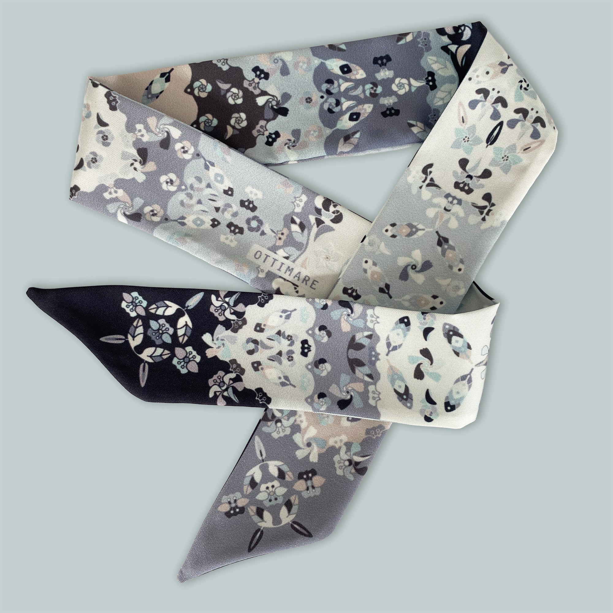 Twilly ladies scarf from Ottimare with grey and black jasmin flowers against a white background. This scarf with a ribbon tie model was handmade from eco friendly art silk in the Netherlands. 