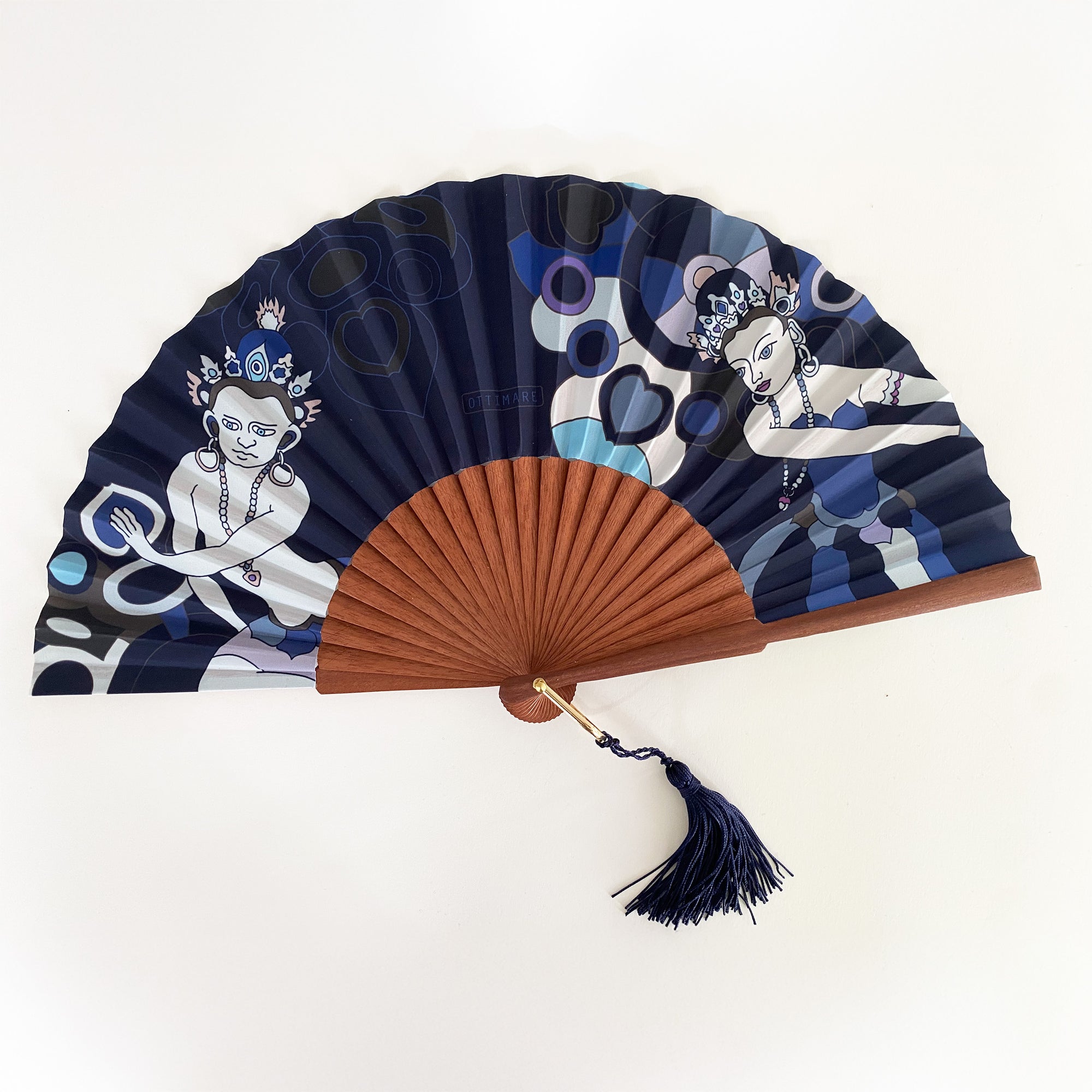 Ottimare waaier met twee Thangka dansers tegen een donkerblauwe achtergrond met een Spaans houten frame in warm bruine kleur met een goudkleurige ring waar een kwastje aanhangt
