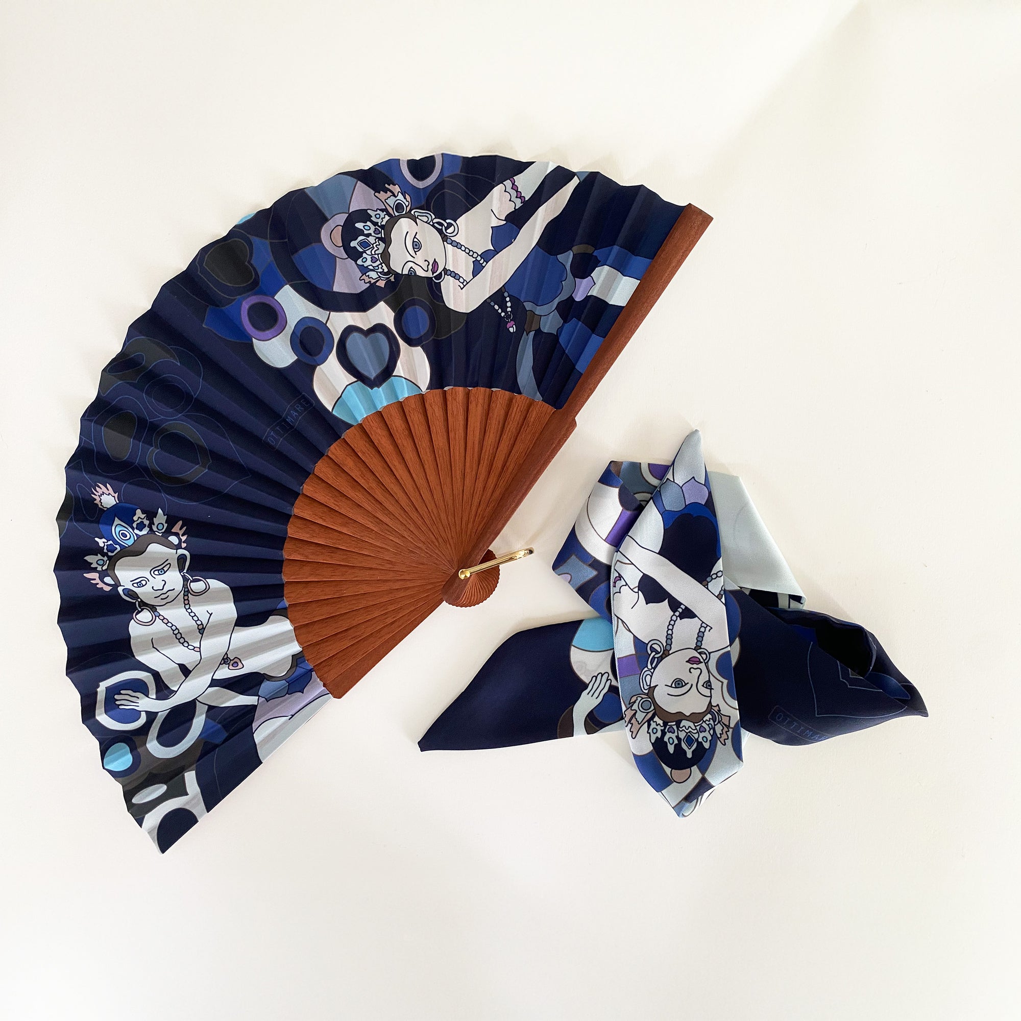 Ottimare waaier met bijpassende twilly sjaal met twee Thangka dansers tegen een donkerblauwe achtergrond met een Spaans houten frame in warm bruine kleur met een goudkleurige ring. 